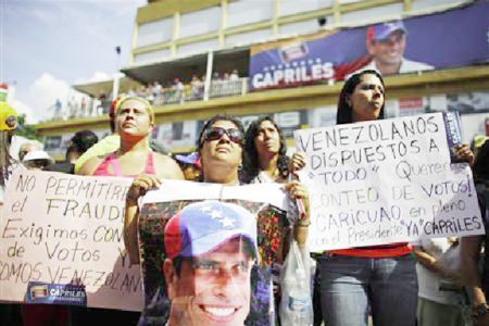 Supporters of opposition leader Henrique Capriles demonstrate in front of Capriles’s campaign headquarters with signs that read, ‘’Venezuelans ready for anything. We want a vote recount’’ (R) and ‘’We won’t allow fraud,’’ in Caracas, April 15, 2013. (Reuters/Tomas Bravo)