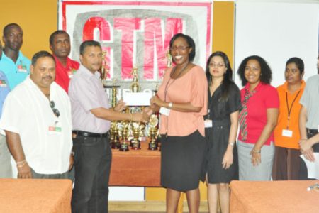 GTM U19 Presentation. GCB secretary Anand Sanasie receives the sponsorship cheque from Yasmin Bowman Group Marketing Officer of the GTM Group of Companies.