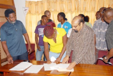 Amateur boxer, Theresa London, affixes her signature to her protocol yesterday in order to receive monthly stipends beginning from May 1 as other boxers GOA’s president, K.Juman Yassin and the top brass of GBA and GOA look on.
