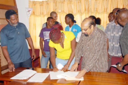 Amateur boxer, Theresa London, affixes her signature to her protocol yesterday in order to receive monthly stipends beginning from May 1 as other boxers GOA’s president, K.Juman Yassin and the top brass of GBA and GOA look on.