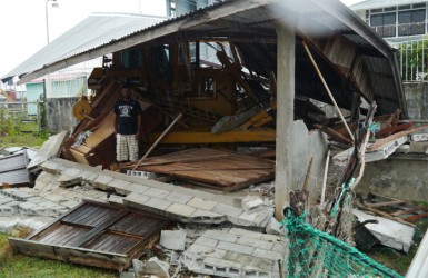 Omesh stands near the bulldozer at the smashed house  
