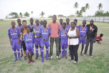 Trophy Stall’s representative Leroy Jack (centre) poses with officials and players of the winning Eagles FC following the presentation. 