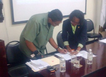 GFC Commissioner James Singh (left) signs the agreement along with FAO Country Representative Dr Lystra Paul 