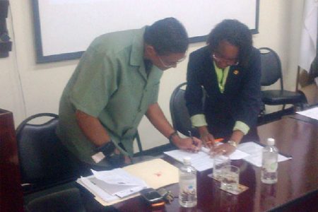 GFC Commissioner James Singh (left) signs the agreement along with FAO Country Representative Dr Lystra Paul 