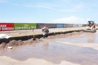 Workers removing silt from a drain along Seawall Road yesterday following severe wave action and overtopping on Sunday and Monday. Householders, businesses and farmers along the coast and in areas such as Bel Air, Subryanville and Campbellville suffered tremendous losses as there was no warning given. (Photo by Arian Browne)  