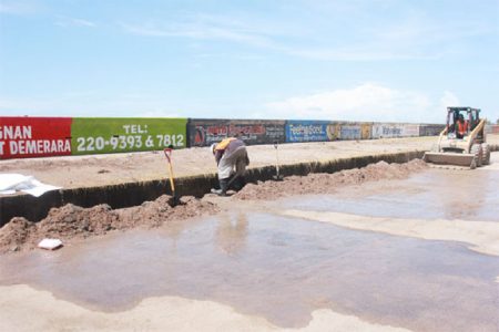 Workers removing silt from a drain along Seawall Road yesterday following severe wave action and overtopping on Sunday and Monday. Householders, businesses and farmers along the coast and in areas such as Bel Air, Subryanville and Campbellville suffered tremendous losses as there was no warning given. (Photo by Arian Browne)  