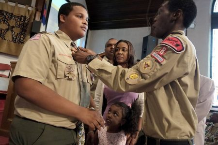 Tevin Barnes (left) receives his Eagle tie from one of his Troop mates while his family looks on. From second left are: his stepfather, Tony Persaud; mother, Wendy Cummings-Persaud and sister Tamia Lynn Persaud.  (New Jersey Star Ledger photo)