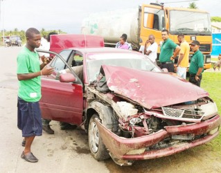 The badly damaged car with the truck in background