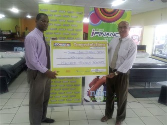 Courts donation- Marketing Manager at Courts Guyana Inc Pernell Cummings (left) handing the cheque to Chairman of the Fundraising Committee of the Guyana Hindu Dharmic Sabha Raj Singh. 