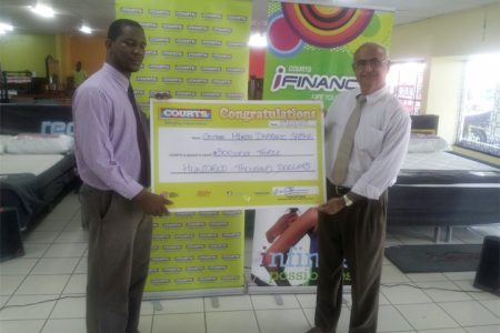 Courts donation- Marketing Manager at Courts Guyana Inc Pernell Cummings (left) handing the cheque to Chairman of the Fundraising Committee of the Guyana Hindu Dharmic Sabha Raj Singh. 