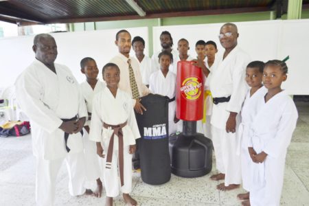 Dhillon De Mendonca (fourth left) presents the equipment to Sensei Winston Dunbar in the presence of other students and instructors.