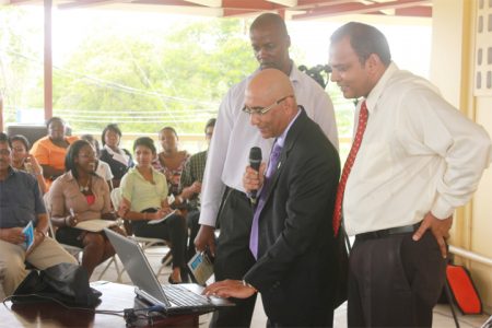 Robin Singh (second from right) demonstrating how the archives works. Minister of Culture, Dr Frank Anthony is at right. (Arian Browne photo)
