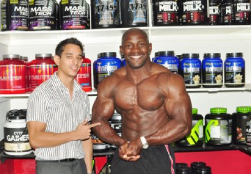 Muscle Mass!  Guest poser of this year’s Novices Bodybuilding Championships, 2012 Mr. Barbados, Stevenson Belle strikes a pose with Fitness Express’ CEO Jaime McDonald at the Sheriff Street entity yesterday. (Orlando Charles photo) 