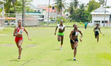 Tirana Mitchell (left) surpasses Onasha Roger (right) to win the girls U-18 100m at the Police Sports Club ground, Eve Leary yesterday.