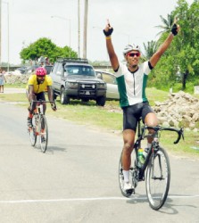 National cyclist, Alonzo Greaves, raises his hand in victory after powering to his eighth signature win of the season yesterday at the Seawall Bandstand. (Orlando Charles photo)