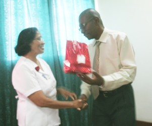 Retired nurse Champawattie Deodat who dedicated over 35 years of service to the health sector receiving her gift from NA Hospital CEO Allan Johnson