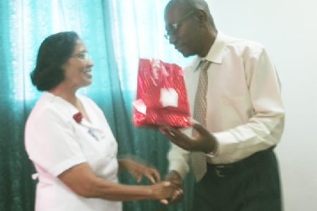 Retired nurse Champawattie Deodat who dedicated over 35 years of service to the health sector receiving her gift from NA Hospital CEO Allan Johnson