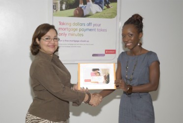 Scotiabank Country Manager Amanda St Aubyn (left) presents Scotiabank MasterCard holiday promotion winner Prudence Edwards with her tickets to Miami. 