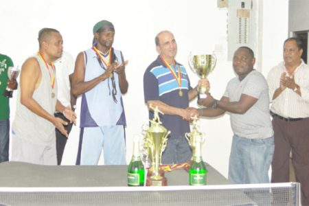 NP Electronics skipper Michael Vieira receives the team’s first place trophy from a member of the Guyana Table Tennis Association.