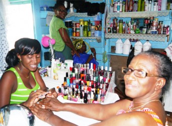 Hazel Wade (standing) washing a client's hair while Shirley is having her nails done