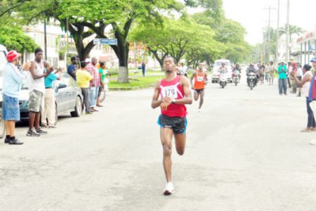 Cleveland Forde crosses the finish line ahead of Trinidad and Tobago-based Kelvin Johnson (behind) at the Athletics Association of Guyana (AAG)/ Ministry of Culture, Youth and Sports (MCYS) Independence Half Marathon yesterday morning.