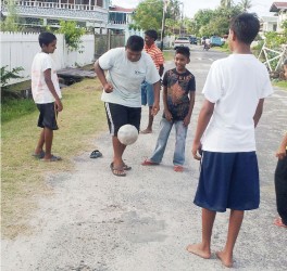  Showing them how it’s done! This group of youngsters looks on as their colleague dribbles a football. 