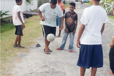  Showing them how it’s done! This group of youngsters
looks on as their colleague dribbles a football. 