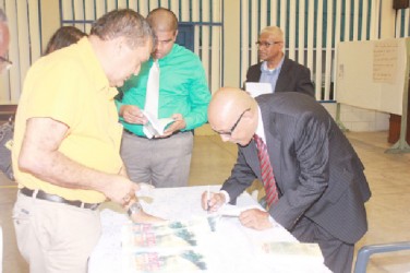Author GHK Lall (right) autographing a copy of his new book, Sitting on a racial volcano (Guyana Uncensored) for Georgetown Public Hospital CEO Michael Khan on Friday. (Photo by Arian Browne) 