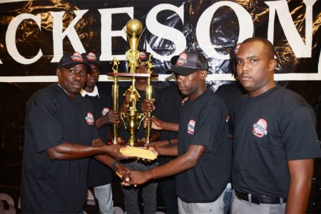 Winning captain Devon Millington (centre) of Sparta Boss collecting Championship Trophy from tournament coordinator Kevin Adonis (left) while Mackeson Brand Coordinator Jamaal Douglas (right) and rest of the team looks on. 
