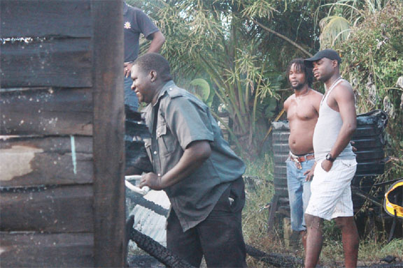 A distraught Mark Smith (right) looks on as fire fighters tackled several pockets of fire at his burnt out home.