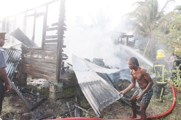 A neighbour assisting fire fighters during yesterday’s blaze at `D’ Field, Sophia.