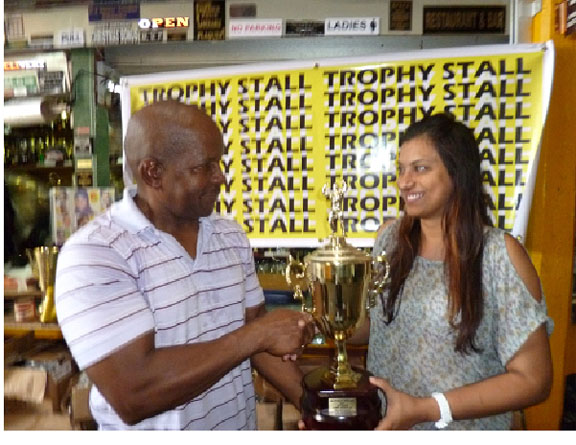 Devi Sunich, wife of Ramesh Sunich, the proprietor of the Trophy Stall hands over the Mr. Fitness Paradise winner’s trophy to Donald Sinclair, owner of Fitness Paradise Gym.