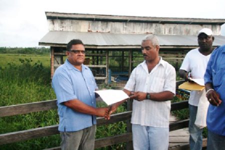 Regional Executive Officer Nigel Fisher (right)  hands over the variation order for the Kumaka-San Jose Bridge to contractor Deodat Singh (GINA photo)