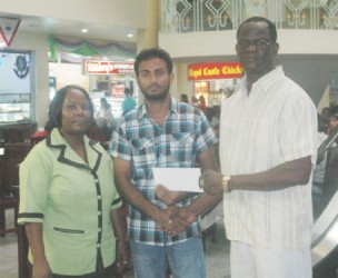 City Mall Supervisor Imran Ayube (centre) hands over the sponsorship cheque to Chairman of the Boyce & Jefford Classic Management Committee, Colin Boyce (right) inside the City Mall while a staff member looks on.