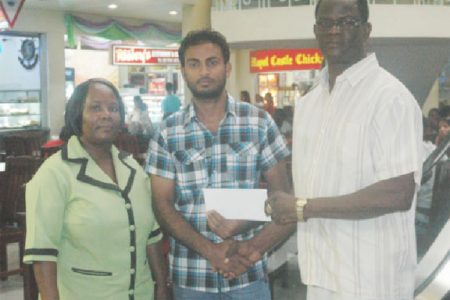 City Mall Supervisor Imran Ayube (centre) hands over the sponsorship cheque to Chairman of the Boyce & Jefford Classic Management Committee, Colin Boyce (right) inside the City Mall while a staff member looks on.