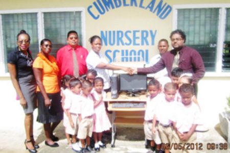 Berbice Chamber of Commerce past president Imran Sacoor (right) presents a computer system to the Cumberland Nursery School at a ceremony attended by pupils of the school and Chamber representatives. 