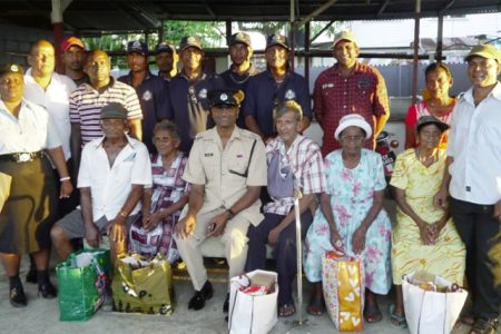 Assistant Superintendent of police, Jiaram Ramlakhan (seated, centre) and others with five of the six residents who received hampers
 