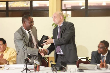 UClan’s Deputy Vice Chancellor Professor Dave Phoenix (right) presents UG’s Vice Chancellor Jacob Opadeyi with a symbol of the partnership their institutions share after the signing of the MOU between the two universities yesterday.
