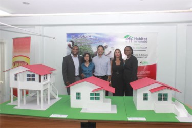 HfHG National Director Rawle Small, Praharshanie Beharry, Beharry Chairman Anand Beharry, Beharry Director Anjuli Beharry, and HfHG’s Communication and Resource Development Manager Colette Hytmiah stand behind the three model homes that qualified families may choose from. The model furthest right is disability friendly. (Photo by Arian Browne) 