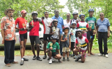 Winners and runners up pose with their trophies upon completion of yesterday’s fourth annual World Olympic Day five-race BMX cycle programme. They are flanked by president of the GOA, K Juman-Yassin (extreme left), Joseph Britton, president of the GCF, Cheryl Thompson and National Cycling Coach, Hassan Mohamed. (Orlando Charles photo)