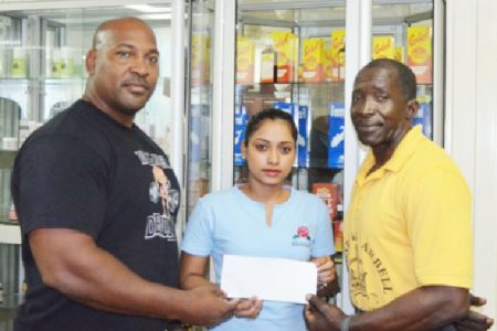 John ‘Big John’ Edwards (left) receiving his sponsorship cheque from Marketing Executive of NEW GPC INC., Livasti Bhooplall as his Kingsrow Barbell gym mate Winston Stoby looks on.
