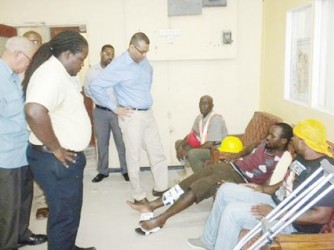 Minister of Natural Resources and the Environment, Robert Persaud (standing first from right) speaking to Fabian Anthony, a survivor of the vehicular accident.  (GINA photo) 