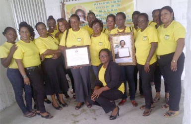 Simona Broomes (stooping) and other members of the GWMO executive with her award.