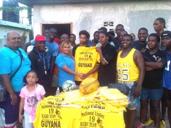 Shenny Lall, manager of the Long Hi Industries presenting a quantity of jerseys to captain of the national under-19 rugby team, Godfrey Broomes in the presence of the coaches, Laurie Adonis and Troy Yhip and other ruggers.