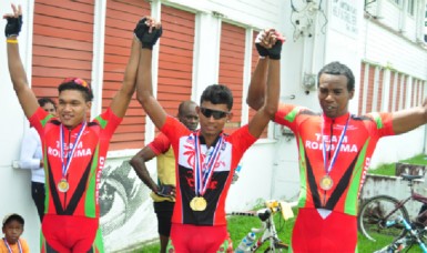 National cyclist, Raynauth Jeffrey (centre) raises the hands of fellow national riders, Alanzo Greaves (left) and Warren ‘40’ McKay after collecting their medals for finishing in the top three of the National Road Race Championships. (Orlando Charles photo) 