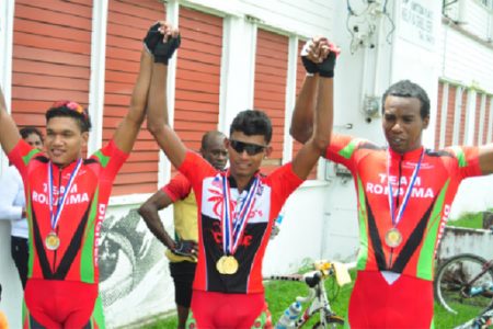 National cyclist, Raynauth Jeffrey (centre) raises the hands of fellow national riders, Alanzo Greaves (left) and Warren ‘40’ McKay after collecting their medals for finishing in the top three of the National Road Race Championships. (Orlando Charles photo)
