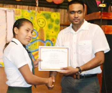 Sylvia Alexander, of Region 9 receives her certificate from Ministry of Amerindian Affairs’ Permanent Secretary Nigel Dharamlall at the Hinterland Scholarship Programme graduation at the Amerindian Village, Sophia on Wednesday. (Government Information Agency photo)