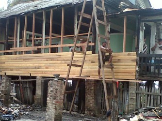 Workmen yesterday rebuilding the wall of Jacqueline Soares’ home, which was burnt in last Saturday’s Quamina Street fire 