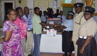In photo, Chairman of the WSMC, Emile Wilson (left in background) presenting the generator to Corporal Avella David in the presence of other officers and members of the WSMC.