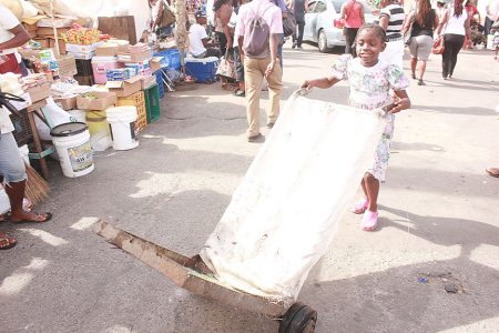 Clear the way! This girl seemed to be having a merry time at Stabroek Market as she pushed her cart yesterday. (Arian Browne photo)